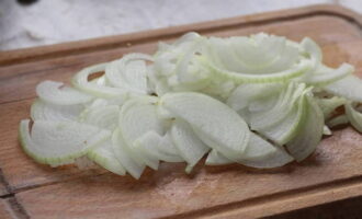 Cut the peeled onion in half. Then cut each half into thin half rings.