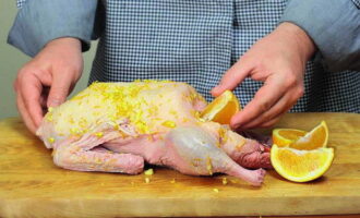 Preheat the oven to 180°C. Cut the second orange into slices and place them in the belly of the bird with a cinnamon stick. Then we seal the hole with a toothpick.