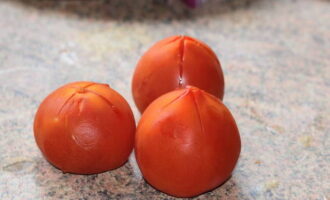 The required number of tomatoes - 3 pieces - must be removed from the skin. To do this, cut the top of each tomato (the cut should be in the shape of a cross) and place them in a deep container. Pour water into a kettle or saucepan and bring to a boil. Then pour boiling water over the tomatoes. After 2 minutes, change the hot water to cold. Now the skin can be easily removed. Cut the tomato pulp into cubes.