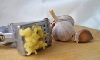 Grind the peeled garlic cloves using a special press.