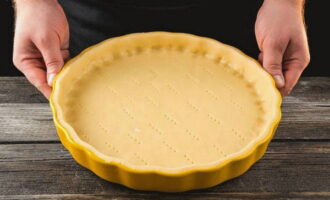 Roll out the dough into a thin layer and distribute it into the baking pan. Using a fork, make punctures around the entire perimeter.