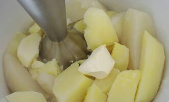 Drain the water from the finished potatoes into a separate container. Now add butter to the potatoes, take a blender and puree everything.