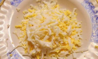 Grate the cooled eggs on a coarse grater and place in a common bowl along with crab sticks.