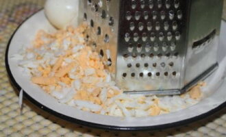 Grate boiled chicken eggs.