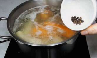 Now add peppercorns to the chicken and vegetables in the pan, then cover the pan with a lid, reduce the heat to low and cook for 1.5 hours. It is important not to let the broth boil too much.