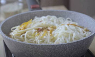 Separately, boil the udon noodles and add them to the dish. Gently stir and remove from the stove. Add green onions and sesame seeds.