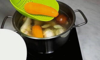 After half an hour, take the carrots out of the broth and transfer them to a plate. 30 minutes before cooking the chicken, add bay leaf and salt to taste to the broth. 