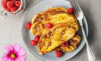 Placez une serviette en papier sur une assiette à fond plat. Déposez dessus les croûtons après la friture pour éliminer l'excès de graisse. Les toasts à l'œuf et au lait dans une poêle sont prêts ! Nous servons le dessert à table. 