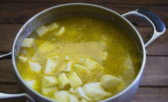 After the time has passed, add potatoes, cut into chaotic large pieces, to the remaining ingredients and fill everything with broth. Season the dish with salt and your favorite spices.