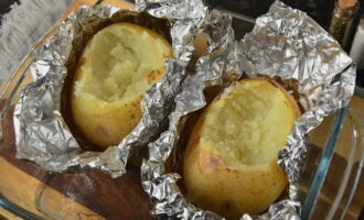 After the potatoes are browned, remove them from the oven. Let the product cool. We remove the peel from the surface of the potatoes and use a fork or spoon to remove the pulp (a small recess should form for the filling). 