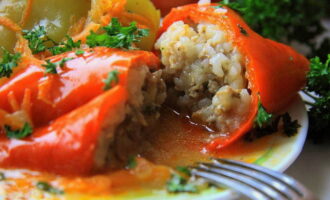 Place the oven on preheat.At the same time, we set the temperature we need - 180 degrees. Place the fried vegetables on a clean baking sheet and distribute them evenly along the bottom of the container. Place stuffed peppers on top of the vegetable mixture. Pour a glass of water into the pan. We push it inside the oven and wait exactly 1 hour.