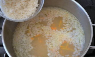 Lave bem o arroz em água corrente até ficar transparente e coloque na panela com o caldo e os legumes. Em seguida, adicione um pouco mais de sal, pimenta preta moída e misture tudo. Cozinhe a sopa por cerca de 20 minutos até que o arroz e as batatas estejam prontos. 