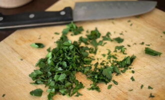 Wash a bunch of fresh parsley under cool water, dry it on a paper towel and chop it with a knife.