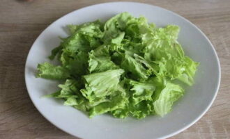 How to prepare a delicious trout salad? We wash the lettuce leaves, dry them, tear them into pieces with our hands and place them on a plate.