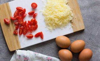 How to cook a fluffy omelette with cheese in a frying pan? Prepare the filling: grate the cheese on a fine or cheese grater, and cut the washed and dried tomatoes into halves or quarters.