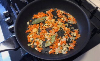 Finely chop the second half of the onion and the garlic clove. Cut the carrots into cubes. Fry onion, garlic and carrots in vegetable oil until soft. Add bay leaf and cook for another 2 minutes.