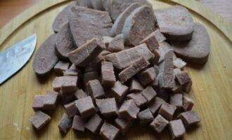 Cut the boiled tongue into large cubes and immediately transfer it to a salad bowl.