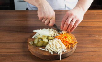 At this time, we will prepare the remaining products. We cut pickled cucumbers into thin slices, carrots, parsley and celery root into thin strips.