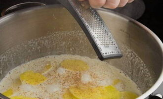 Place the potatoes in a saucepan, pour in the cream and boil the vegetable for 10 minutes. Then add chopped garlic, salt, nutmeg and ground pepper.