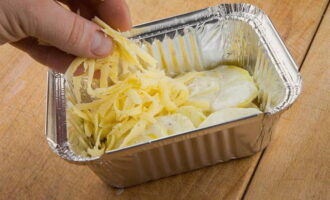 Grease a baking dish with vegetable oil and lay out layers of potatoes and cheese, alternating them. Pour cream over everything.