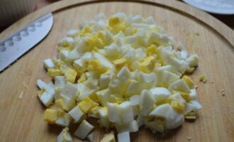 Peel the hard-boiled eggs, cut into small cubes and add to the salad bowl.