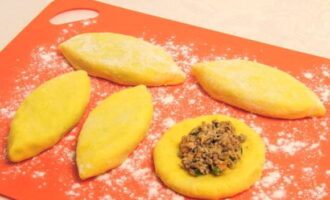 Sprinkle the working surface with flour. Scoop the potato dough with a spoon, form it into a ball and knead it into a flat cake. Place the filling in the center and seal the edges.Breaded in flour.