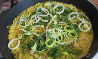 Stir the rice and taste to see if it needs more salt. Close the lid and cook over low heat until done. Chop the greens and leeks. When the rice has absorbed all the liquid again and is ready, open the lid and sprinkle it with herbs and onions.