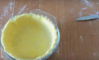 Roll out the chilled dough into a thin flat cake and place it in a baking dish, forming sides along the edge.