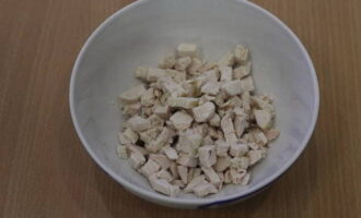 How to make a salad with chicken, pineapple and walnuts? The boiled chicken breast is cut into small cubes and placed in a salad bowl.