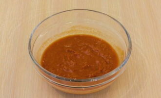 Transfer the tomato paste into a small container, add wheat flour to it and mix thoroughly. Then pour in 100 ml of water at room temperature and mix again.