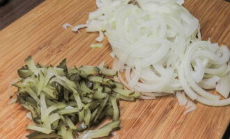 Cut the pickled cucumbers into strips. Cut the peeled onion into thin half rings. Place the onions and cucumbers in a salad bowl, mix the ingredients so that they are saturated with each other’s juice.