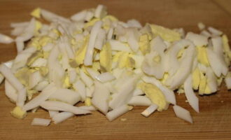 When the carrots and eggs have cooled, you need to peel them and cut them into strips. Transfer the ingredients to the salad bowl, along with the onions and cucumbers. 