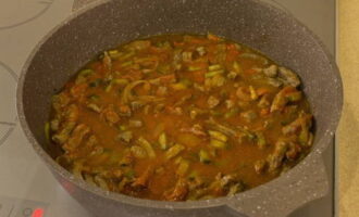 Now pour in the tomato paste sauce, pour in a little more water so that it slightly covers the meat, then cover the pan again with a lid and simmer the meat for another hour.