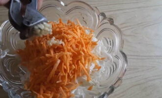 The carrots are peeled, washed and chopped on a coarse grater. Then it is transferred to the cabbage. Add two cloves of minced garlic to the salad.