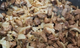 Chop the onions, peeled and washed with running water, into quarter rings, add them to the fried beef and fry a little.