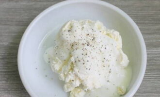 Fersk cottage cheese legges i en egen kopp. Deretter tilsettes fet rømme, som kan erstattes med enten naturlig yoghurt eller kefir. Hytteosten er drysset med salt og sort pepper etter din smak.