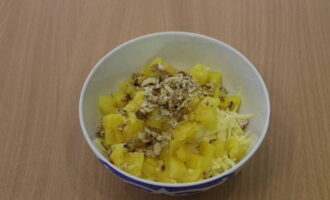 Peeled walnuts are crushed with a knife or blender. Pineapple is cut into the same pieces as chicken. These ingredients are transferred to a salad bowl.