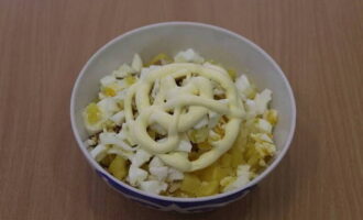 Then hard-boiled chicken eggs are crushed and added to the salad bowl. The salad is slightly salted and dressed with mayonnaise sauce. Next, it is mixed with a spoon.