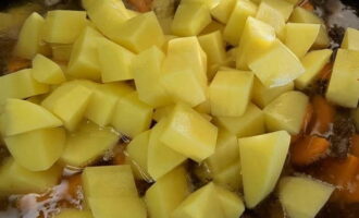 Cut the peeled potatoes into small cubes and place in a cauldron. Then add enough hot water to these ingredients to completely cover the meat and vegetables. Cook everything over medium heat for 10 minutes.