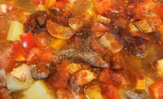 Chop the washed bell peppers and tomatoes into small cubes and place in a cauldron.Then sprinkle the dish with salt and black pepper to your taste, add ground paprika and chopped garlic cloves. After boiling, simmer the meat and vegetables over low heat and covered with a lid for about 40 minutes, until the beef is cooked.