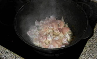 Place the cauldron on the stove, heat it up, pour in sunflower oil. Next, add the chicken and fry it until golden brown.