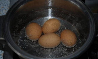 Fill the eggs in a saucepan with cold water. When the liquid boils, set the time for 7-10 minutes, during which the eggs will cook. Then drain the boiling water and pour cold water into the pan with the eggs again. When the eggs have cooled, drain the liquid, wipe the product with a towel and peel. Cut into small cubes.