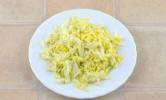 Let's start with the filling: grate the boiled and peeled eggs on a coarse grater.