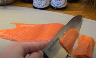 Using a sharp knife, the red fish fillet is separated from the skin and cut into thin slices. The fillet for such sandwiches is lightly salted, as it goes best with avocado, as opposed to smoked. 