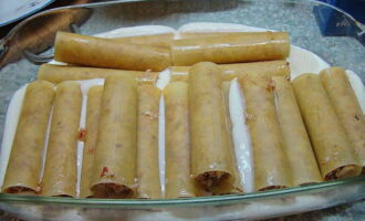 Pour one half of the prepared sauce into the baking dish. Place the stuffed cannelloni in the sauce.