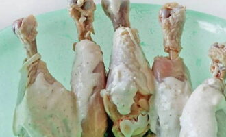 Wash the chicken legs and dry with a napkin. Using a knife, cut the meat at the base of the legs so that the bone is exposed a little, as papillots are put on the drumsticks. Place the prepared legs into a separate bowl, coat well with the rest of the sour cream sauce and leave to marinate for 30 minutes.