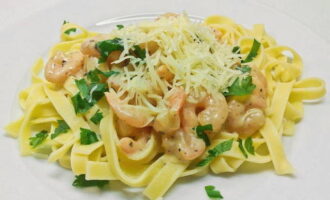 Cook the pasta as directed on the package. Then pour a glass of cold water into it and after 2 minutes, drain the pasta in a colander. This method will make the pasta soft and not mushy. Place the cooked pasta on serving plates, pour over the creamy shrimp sauce, sprinkle with grated cheese and herbs, and serve. Bon appetit!