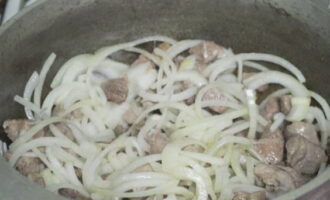 When the meat turns slightly white, add onions, cut into half rings, and simmer until the vegetable is transparent.