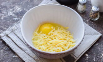 Break an egg into a deep bowl and add hard cheese, crushed using a grater.