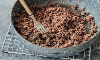 Then add minced meat and chopped garlic to the fried onion and mash it thoroughly with a fork until fine and homogeneous. Fry the minced meat for no more than 10 minutes over medium heat and stir occasionally.